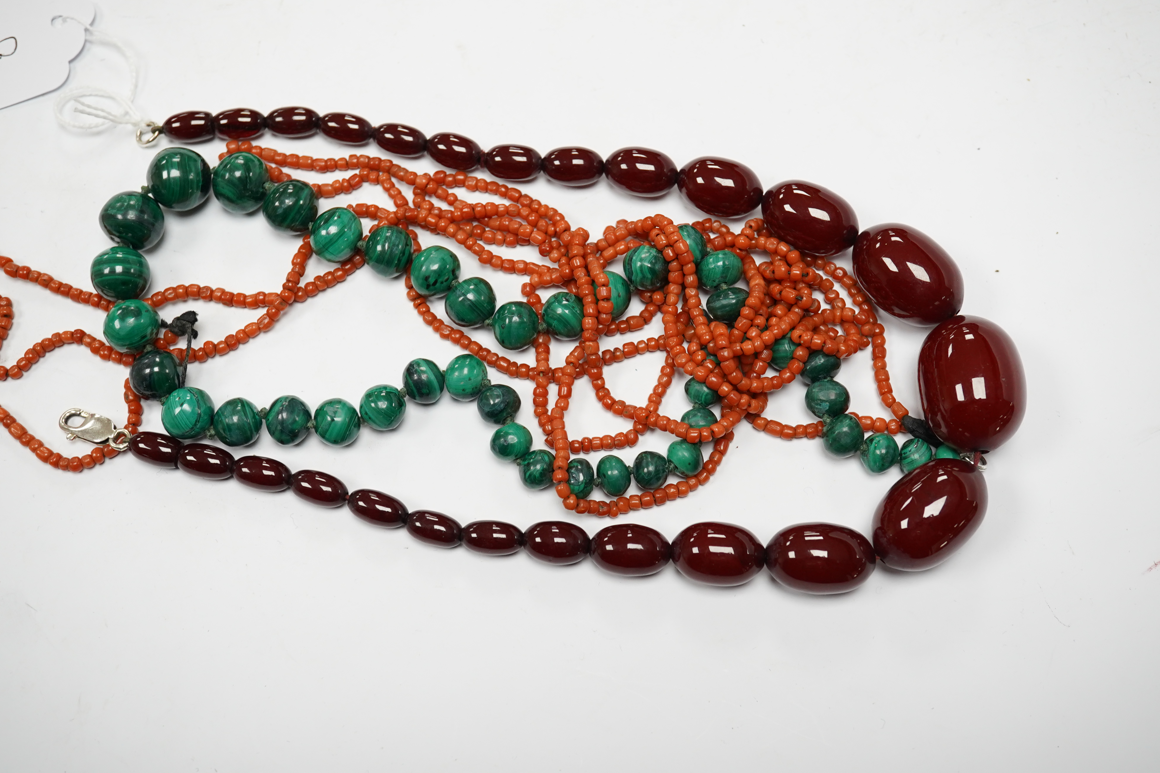 A graduated simulated cherry amber bead necklace, 43cm, gross weight 54 grams and two other necklaces including malachite. Condition - fair to good